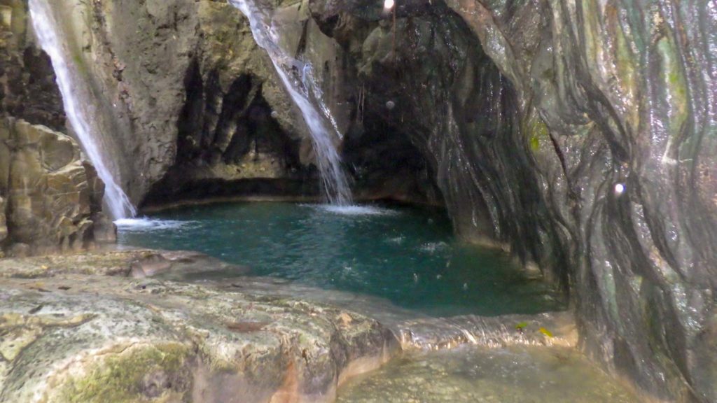 waterfalls splash into a limestone pool of clear water