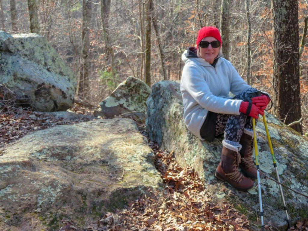 Woman sits on a boulder in the forest